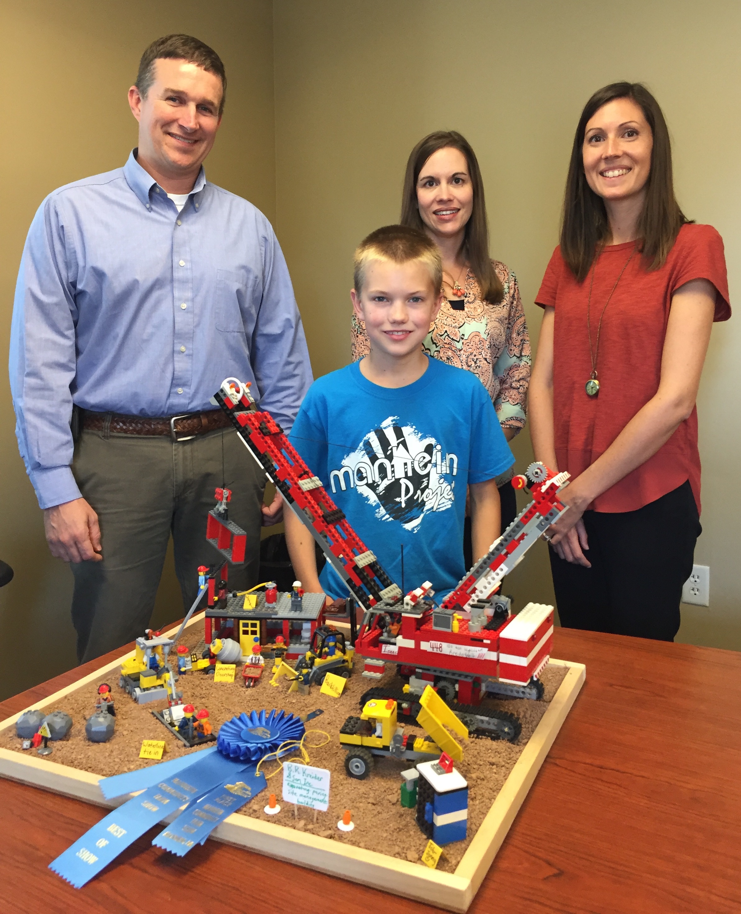 Isaac Kreider (front) displays his Best In Show LEGO creation based on a B.R. Kreider & Son worksite with the company’s fourth generation leadership team (l-r); Brent Kreider, Heidi Hollinger, and Courtney Dougherty.